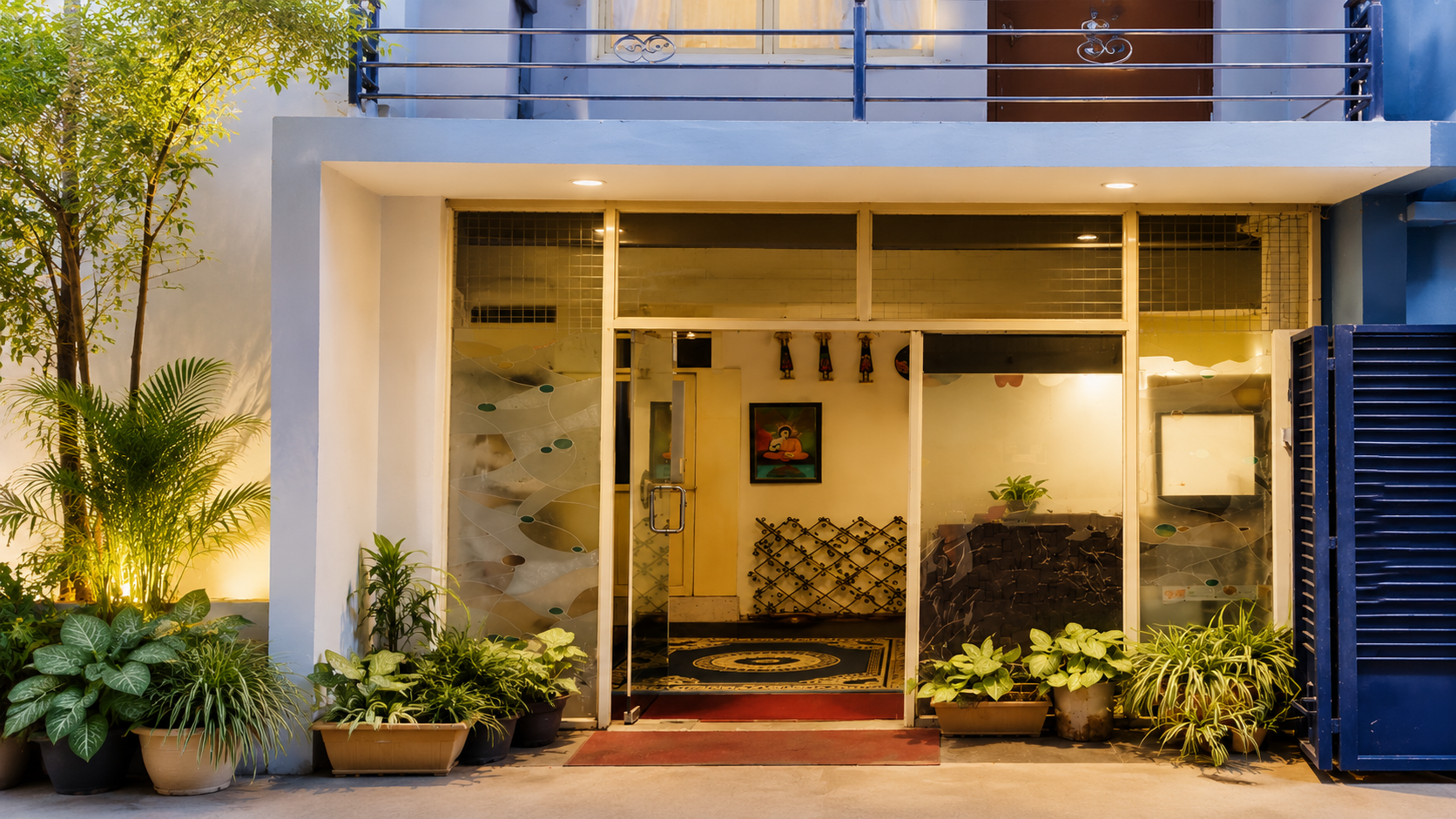 Aster Vue Hotel lit entrance with potted plants at dusk